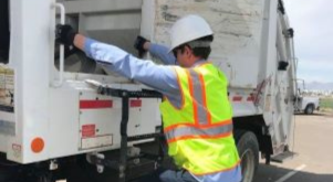 Solid waste employee about to step onto a vehicle