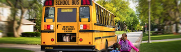 children running toward school bus on road in neighborhood