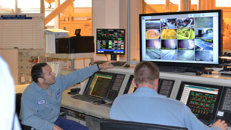 Two workers watch a monitor